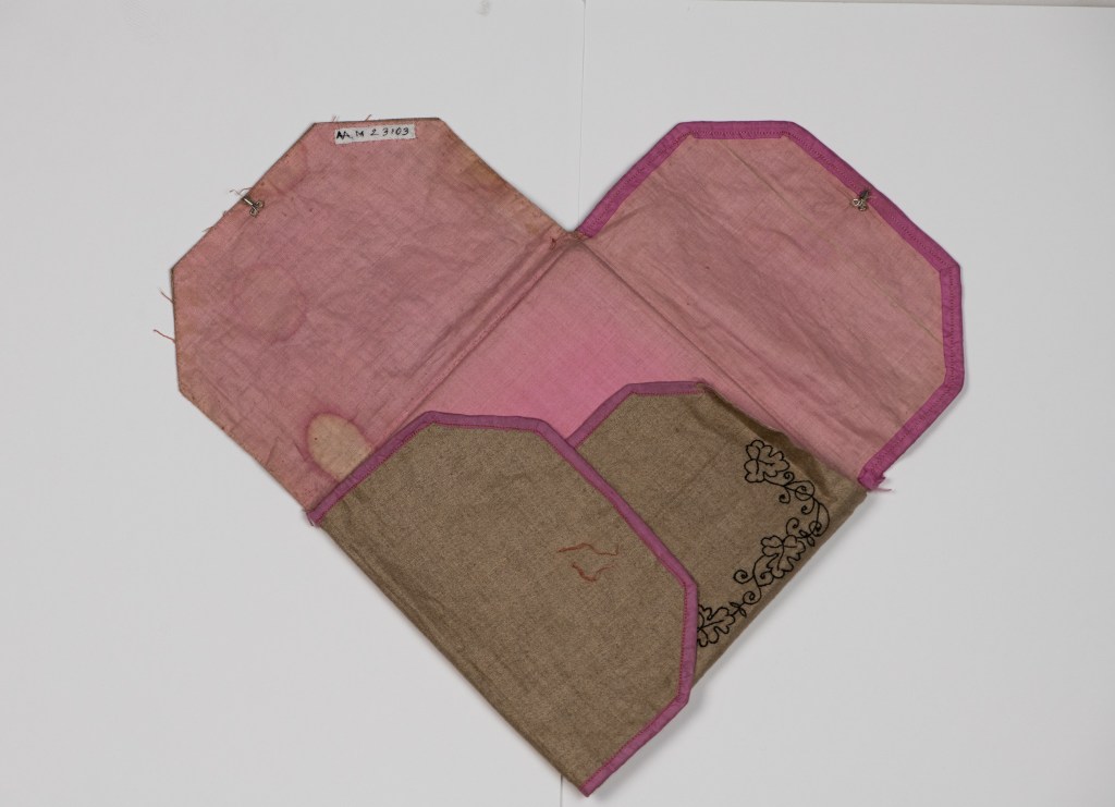 Eldre stoffbitar i eit hjerteforma mønster med rosa og brun farge, og dekorativ broderi.